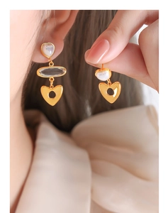 Gros plan de boucles d'oreilles cœur dorées avec perles et breloques sur un modèle