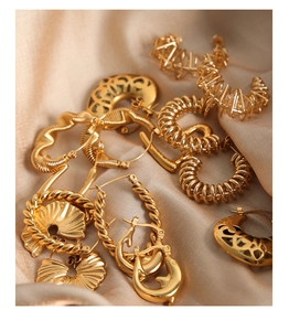 Detailed view of various vintage 18K gold-plated twisted hoop earrings on beige silk fabric