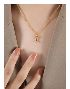 Close-up of gold Gemini zodiac pendant necklace with sparkling zircons on female model
