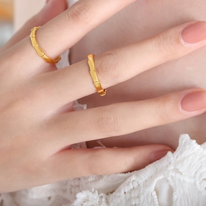 Minimalist gold-tone bamboo joint rings shown on a hand with lace detail background