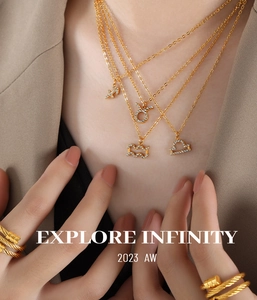 Detail of gold zodiac pendants with zircon inlays and woven ring on model in casual suit