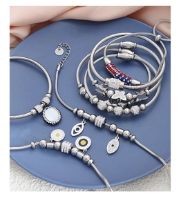 Detailed shot of silver steel charm bracelets with butterfly and heart charms on blue plate