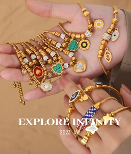 Detail of gold bracelets featuring evil eye, heart charms and roman numeral engravings