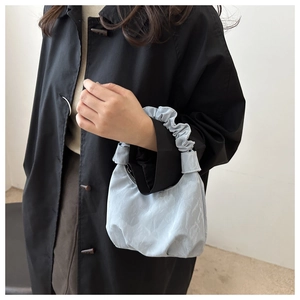 Gros plan sur la poignée froncée en forme de nuage bleu clair du sac à main chic