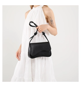 Détail du sac bandoulière noir avec rabat ondulé et poignée nouée élégante
