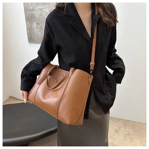 Brown soft PU tote bag with vertical stitching shown on model with shoulder strap