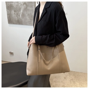 Detail of khaki PU leather tote bag with long shoulder strap worn on black shirt