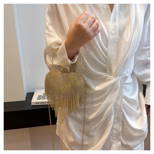 Detailed view of a gold heart-shaped evening bag featuring sparkling rhinestones and tassels
