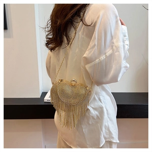 Close-up of golden heart-shaped clutch with rhinestones and long tassels on chain