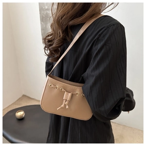 Detail view of light brown leather underarm bag with drawstring and gold eyelets