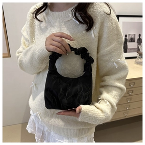 Détail d'un sac à main noir avec poignée plissée et textures satinées élégantes