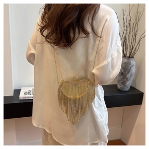 Detail of a golden heart evening bag with crystal rhinestones and metal tassels