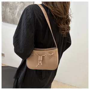 Detail of khaki drawstring shoulder bag featuring matte leather and gold eyelets