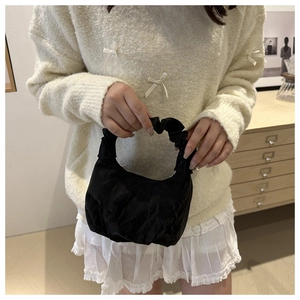 Détail d'un sac à main noir plissé en nylon avec poignée froncée porté par un modèle