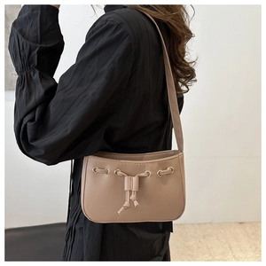 Detail of tan faux leather shoulder bag featuring gold eyelets and drawstring accents