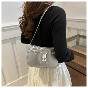 Detail showing shiny silver metallic handbag surface with gold eyelets and drawstring