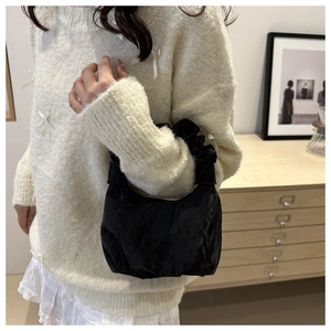 Détail du sac nuage noir plissé avec anse à volants et texture de tissu mat