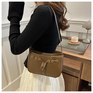 Detail of dark khaki baguette bag showing metallic eyelets and drawstring decor