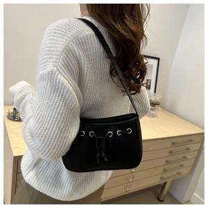 Detail of minimalist black crescent bag with golden eyelets and drawstring on a model