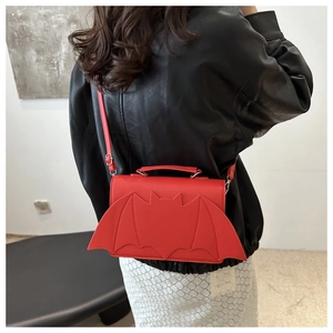 Red bat-shaped crossbody bag shown on a model with adjustable strap and gothic wings