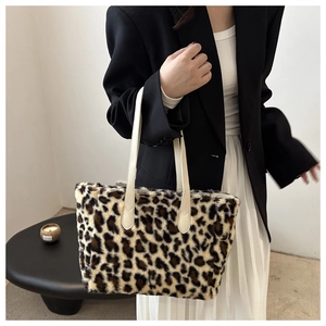 Detail view of leopard print plush tote bag with white leather handle and soft texture