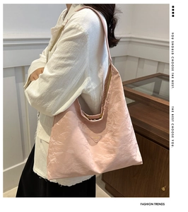 Dettaglio della borsa tote in nylon rosa con placca triangolare e texture pieghettata