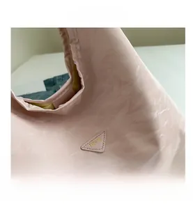 Detail of light pink tote bag with textured surface and triangular fashion patch logo