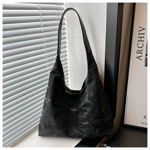 Detail of black tote bag featuring a vintage pleated texture and silver triangle logo
