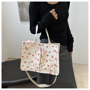 Détail du sac cabas en toile blanche à motif cerise et deux poches frontales