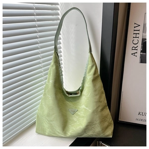 Detail of light green hobo bag with textured fabric and fashion triangle logo on front