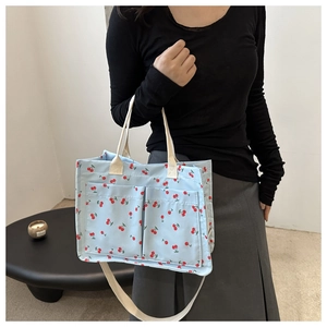 Détail d'un sac cabas en nylon bleu à motif cerises avec des poches avant fonctionnelles