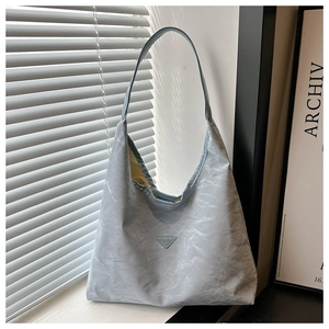 Macro detail of large light blue hobo bag with pleated texture and triangle metal plaque