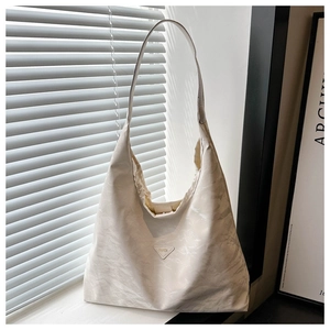 Detail of minimalist ivory tote bag featuring textured fabric and triangular logo plate