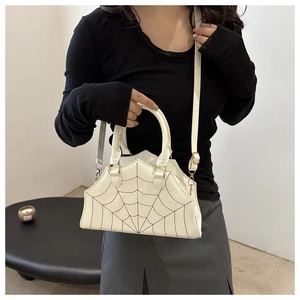 Detail of off-white crossbody bag with black spider web embroidery and top handle
