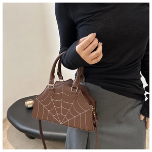 Detail of a brown PU handbag featuring a white spider web embroidery and adjustable strap