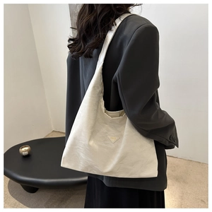 Detail of cream tote bag with pleated texture and fashion label worn over the shoulder