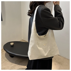 Detail of a beige pleated texture hobo shoulder bag with fashion triangle label