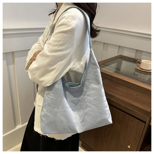 Detail view of light blue tote bag with ruched texture and triangular metal plaque