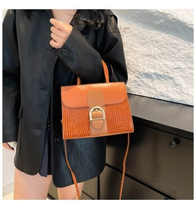 Detail of stone pattern texture and horse-bit buckle on the brown patchwork tote bag