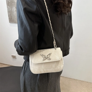 Chic cream mini crossbody bag with silver butterfly buckle shown on model shoulder