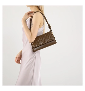Detail view of dark brown quilted shoulder bag with decorative knotted strap on a model