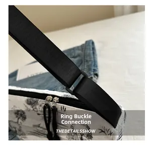 Detail showing the adjustable black nylon shoulder strap and dual zipper of the ink-print bag