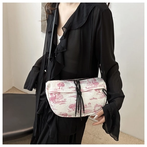 Detail of crossbody bag with red Toile de Jouy pattern and black drawstring puller