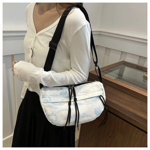 Detail of white textured crossbody bag featuring blue landscape print and adjustable strap