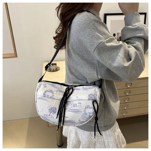 Detail of half-moon crossbody bag with purple landscape print and black drawstring accent