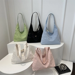 Borse tote minimaliste in nylon a pieghe in cinque colori esposte su un podio bianco
