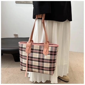Detail of classic plaid tote bag with pink straps and textured canvas material