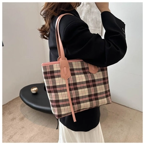 Side view of a large pink plaid tote bag worn by a model in a modern interior