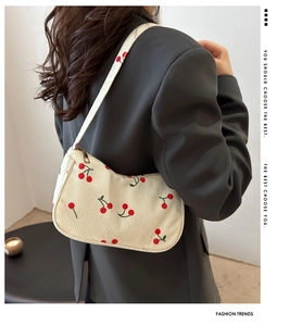 Detail of white corduroy underarm bag with red cherry embroidery and zipper closure