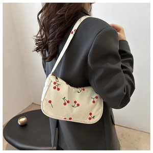 Dettaglio della borsa a spalla in velluto bianco con stampa ciliegia abbinata a un blazer